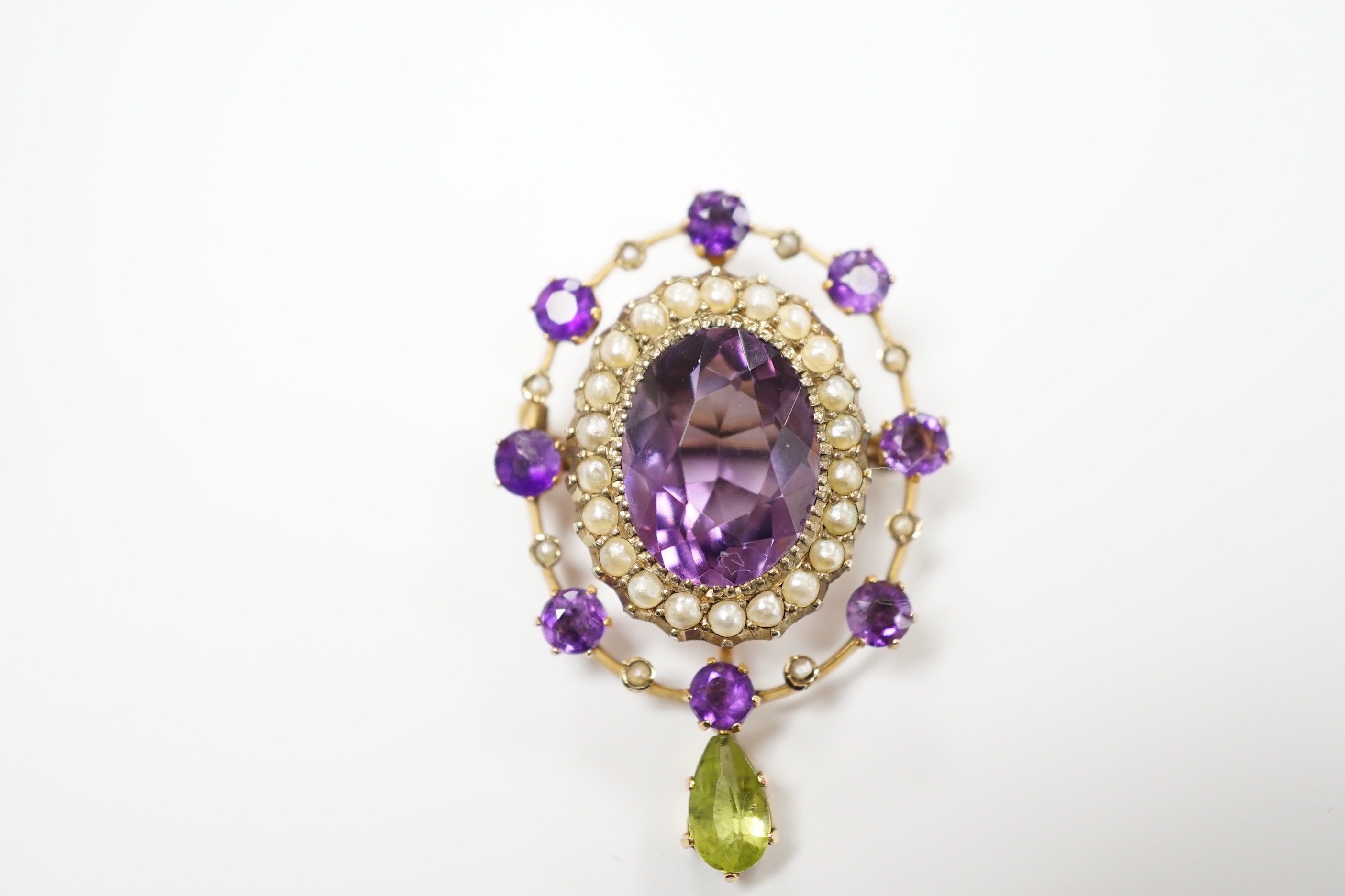 An early 20th century yellow metal, amethyst, peridot and seed pearl cluster set drop pendant brooch, 35mm, gross weight 4.9 grams.